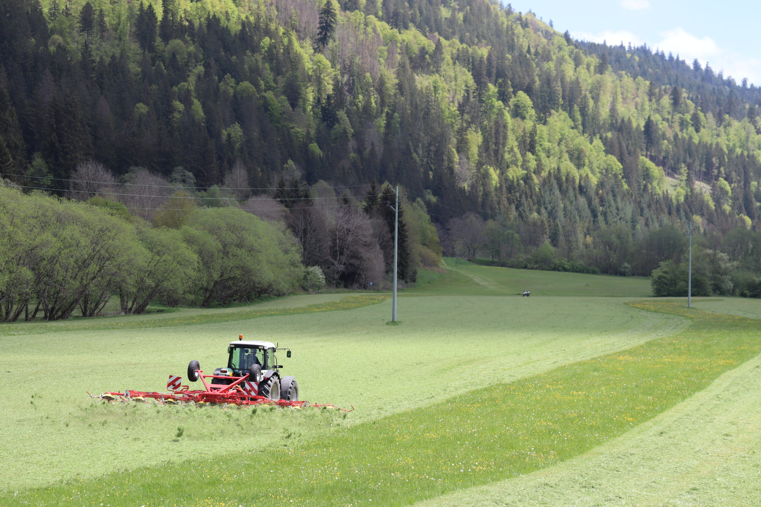 Landwirtschaftsmaschine fährt durch Grünland neben einem Schonstreifen.