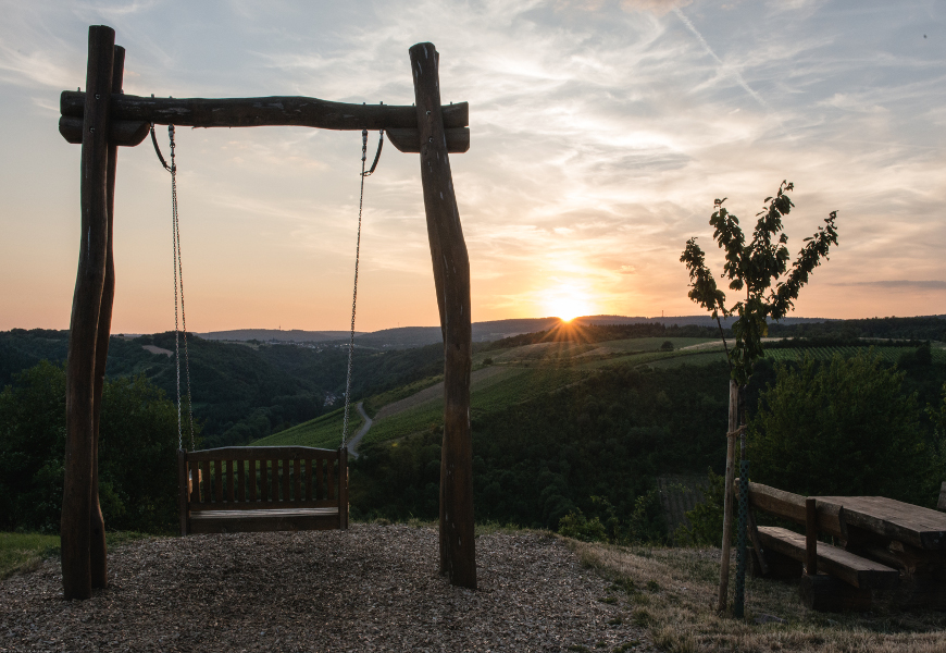 Eine Schaukel mit Weitblick über eine Landschaft, während die Sonne untergeht