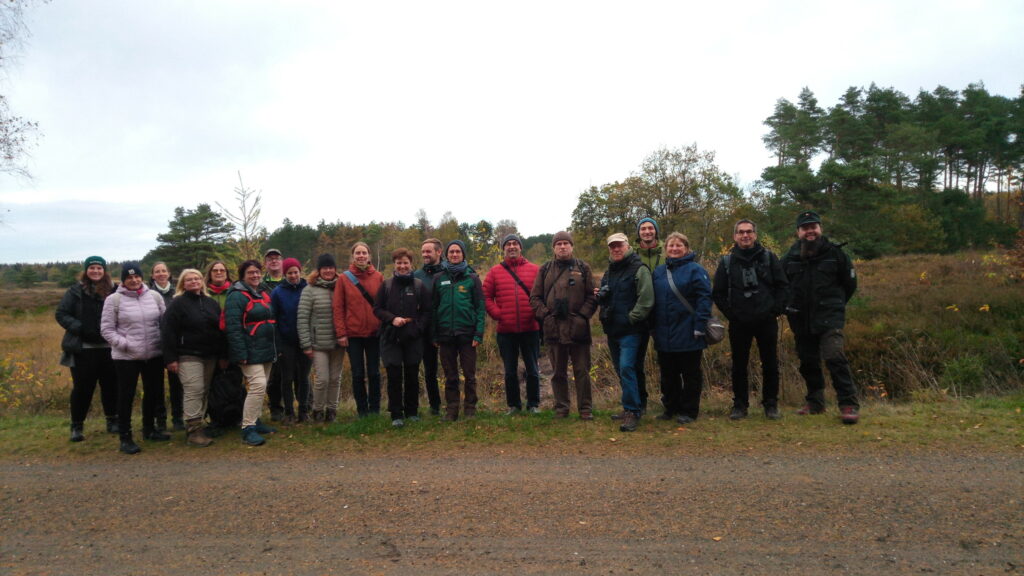 Gruppe von rund 20 Personen in einer Reihe mit Blick zur Kamera