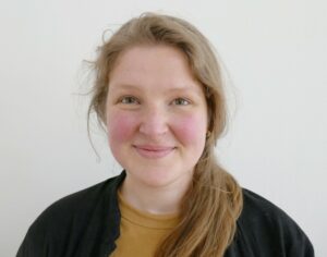 Porträt einer blonden, freundlich lächelden Frau mit Sommersprossen